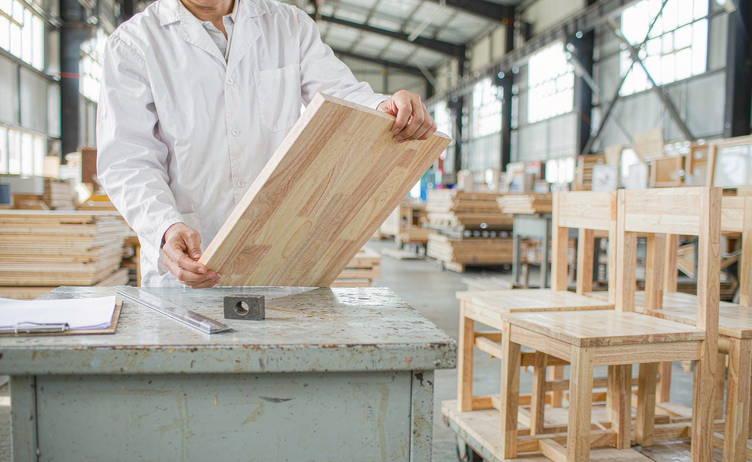 Técnico de control de calidad inspeccionando un panel de madera en el taller de la fábrica.