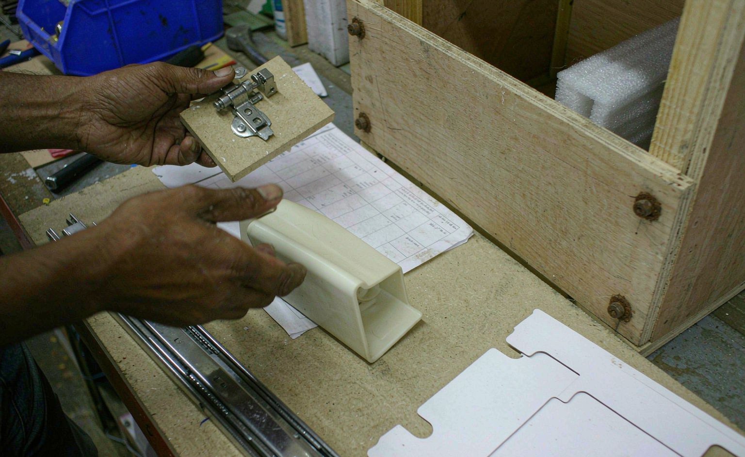 Técnico revisando bisagras y guías homologadas junto a muestras de acabado antes del packing de exportación