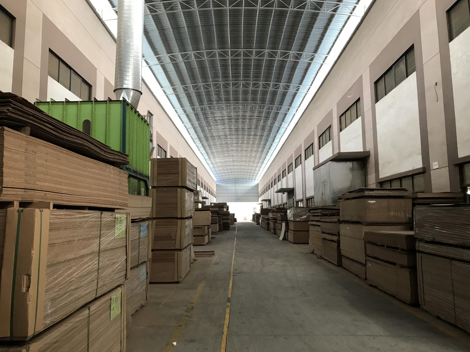 Almacén de fábrica con lotes de panel de madera apilados antes del embalaje.