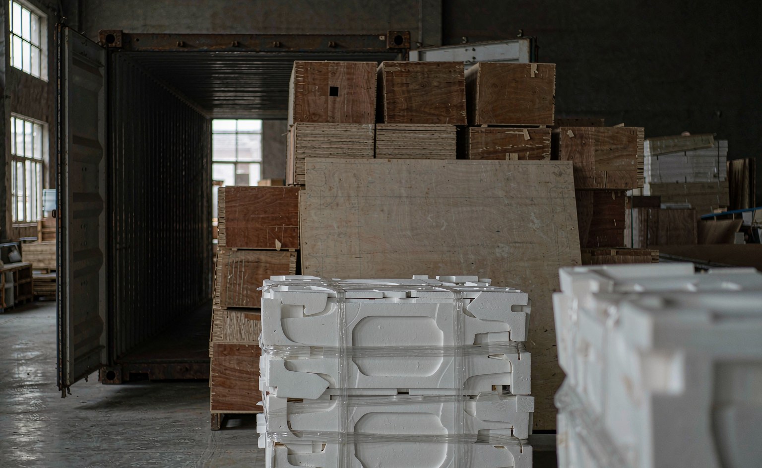 Cajas de madera contrachapada sobre palé con protección de espuma EPE junto a un contenedor abierto