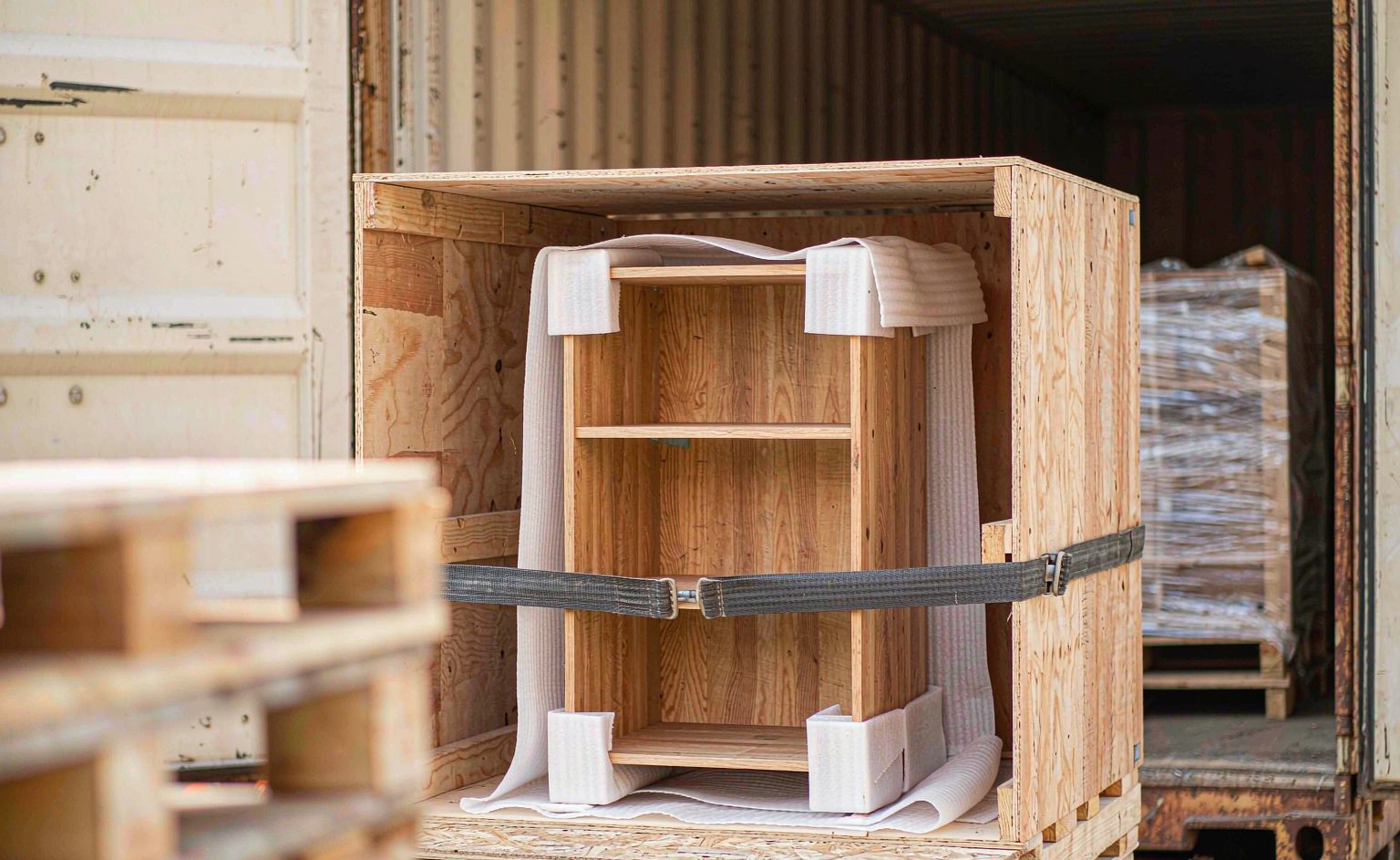 Estantería de biblioteca envuelta en espuma y esquineros dentro de una caja de madera contrachapada sujeta sobre un pallet