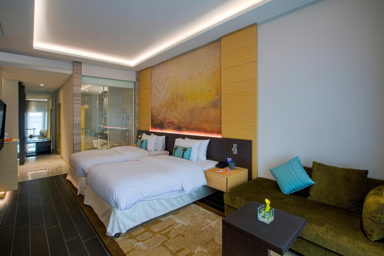 Habitación de hotel con cama, cabecero y sofá del equipamiento FF&E de un proyecto.